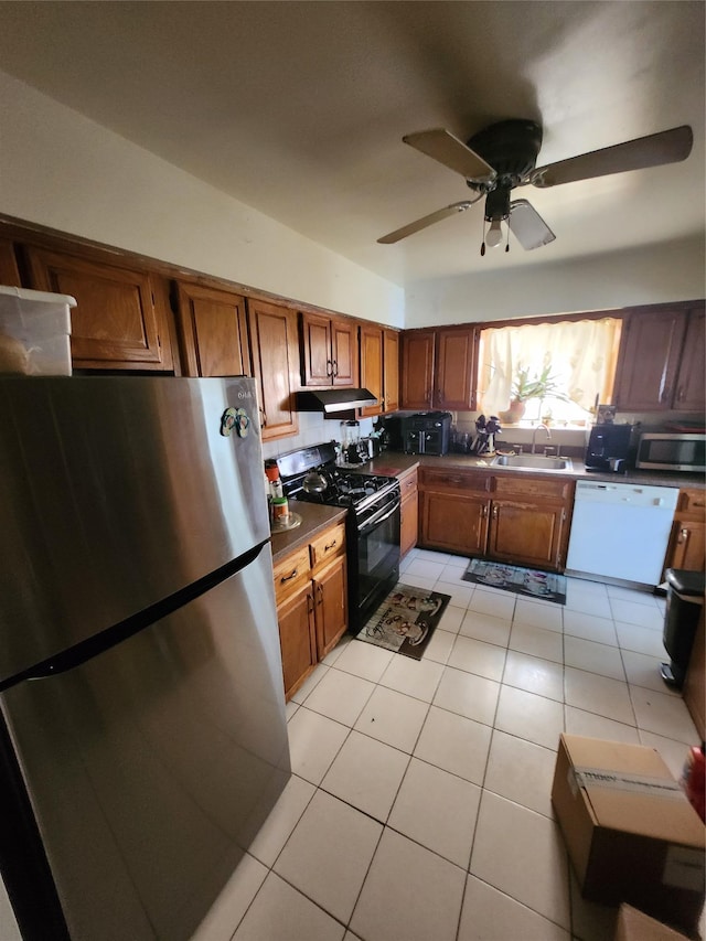 kitchen featuring under cabinet range hood, appliances with stainless steel finishes, brown cabinets, and a sink