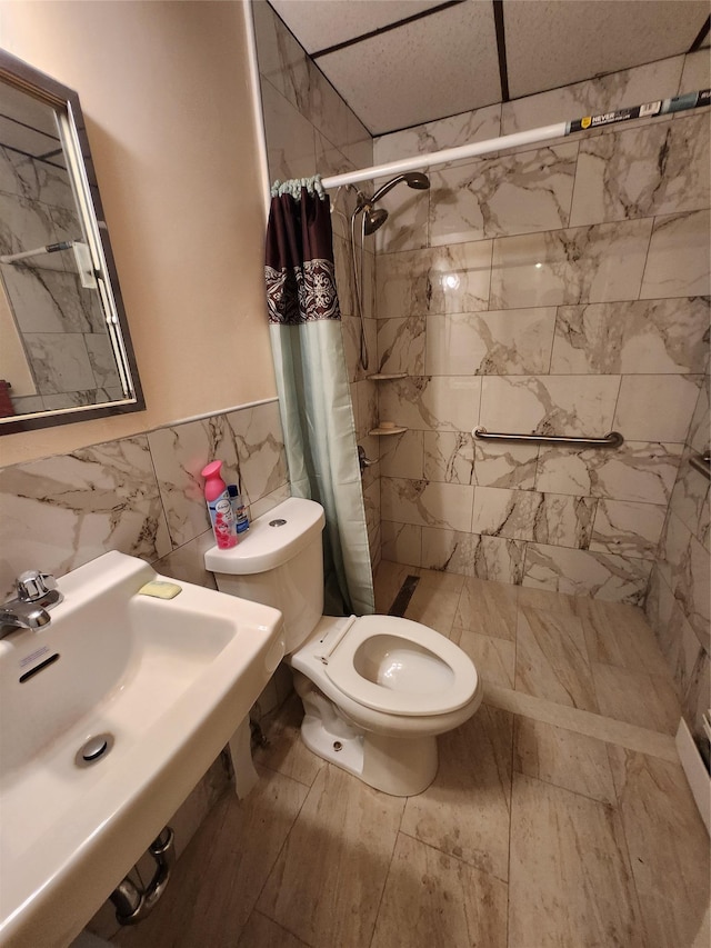 full bathroom featuring tile walls, a sink, toilet, and a shower stall