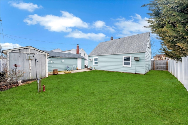 back of property with a fenced backyard, a shingled roof, an outdoor structure, a lawn, and a shed