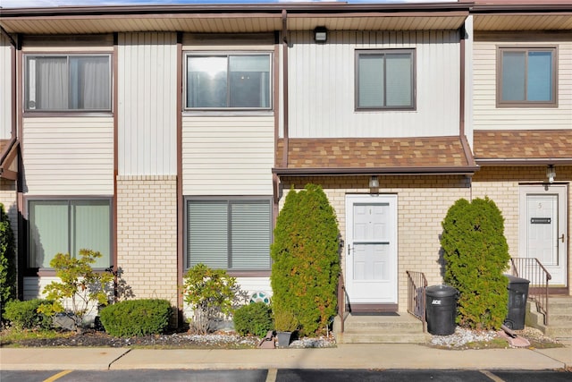 multi unit property with a shingled roof and brick siding