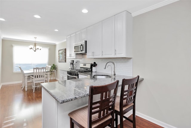 kitchen featuring decorative backsplash, light stone counters, stainless steel appliances, crown molding, and a sink