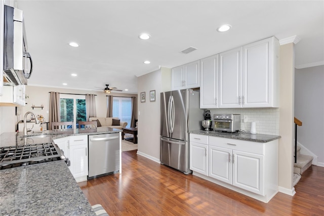 kitchen featuring appliances with stainless steel finishes, white cabinetry, dark wood-type flooring, and decorative backsplash