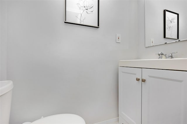 bathroom with vanity, toilet, and baseboards