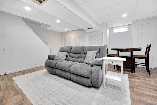 living room with a paneled ceiling, visible vents, and wood finished floors