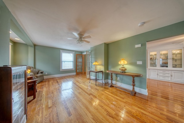 sitting room with a ceiling fan, baseboards, and wood finished floors