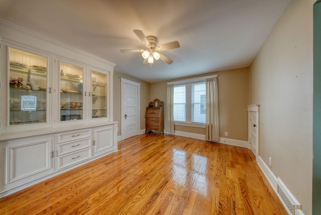 spare room with baseboards, a ceiling fan, visible vents, and light wood-style floors