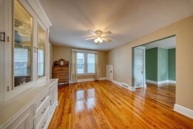 empty room with light wood-type flooring, visible vents, baseboards, and ceiling fan