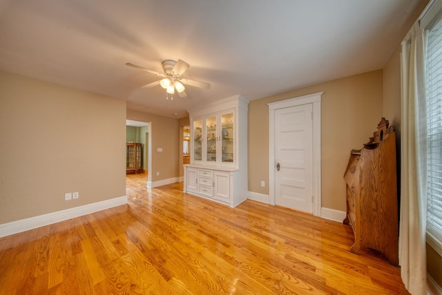 unfurnished room with light wood-style flooring, baseboards, and a ceiling fan