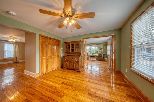 interior space with baseboards, a ceiling fan, and light wood-style floors