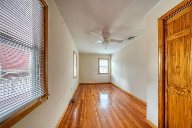 unfurnished room with visible vents, baseboards, wood-type flooring, ceiling fan, and ornamental molding