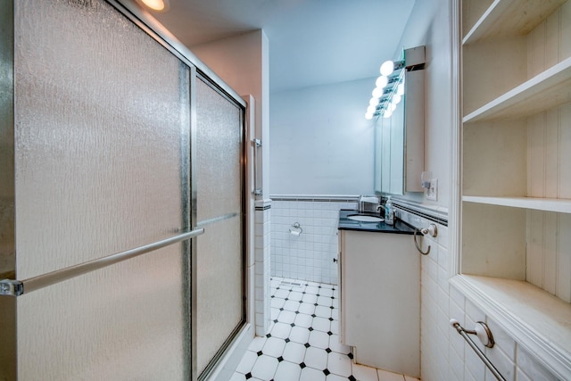 bathroom featuring vanity, wainscoting, a shower stall, and tile walls