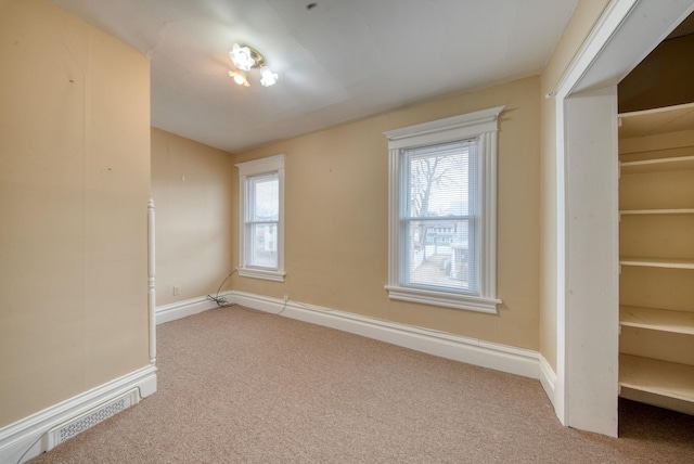 carpeted spare room with visible vents and baseboards