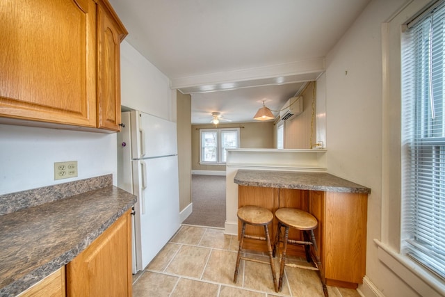 kitchen with a wall unit AC, dark countertops, light tile patterned floors, and freestanding refrigerator