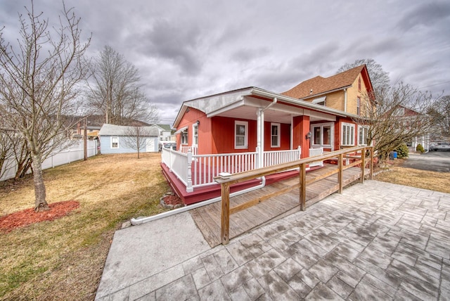 view of front facade with a porch, a front yard, fence, and an outdoor structure