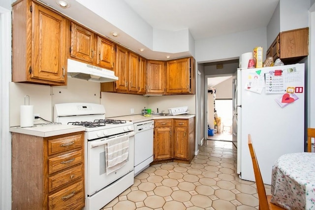 kitchen with light countertops, white appliances, brown cabinetry, and under cabinet range hood