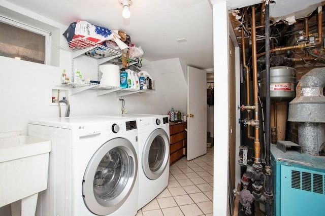 clothes washing area featuring washing machine and dryer, laundry area, light tile patterned flooring, and a sink