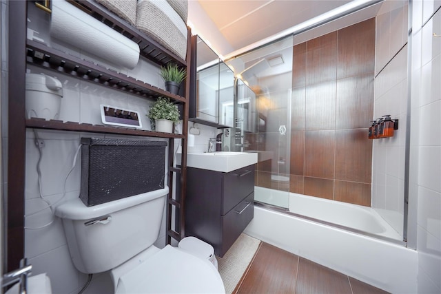 full bath featuring vanity, toilet, and bath / shower combo with glass door