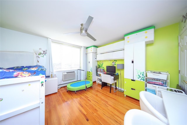 bedroom featuring light wood-style flooring, a wall mounted air conditioner, baseboard heating, and ceiling fan