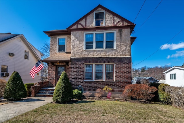 tudor home with brick siding, cooling unit, and a front lawn