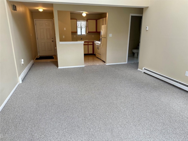 unfurnished living room with light carpet, a baseboard heating unit, baseboards, and a sink