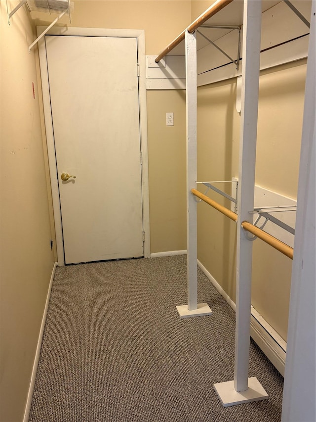 walk in closet featuring a baseboard heating unit and carpet