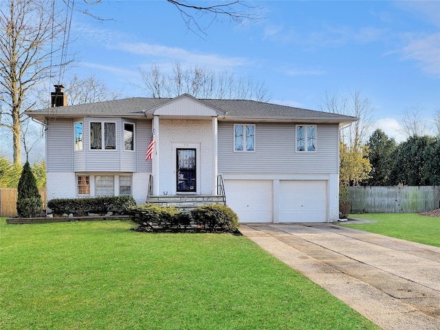 raised ranch with concrete driveway, brick siding, a chimney, and a front lawn