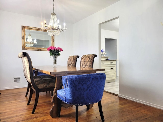 dining area with a chandelier, dark wood-style flooring, visible vents, and baseboards