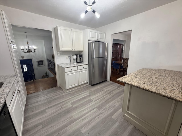 kitchen featuring light wood finished floors, dishwasher, freestanding refrigerator, an inviting chandelier, and white cabinetry