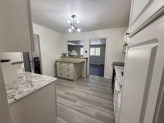 kitchen featuring light stone countertops, light wood-style floors, baseboards, and an inviting chandelier