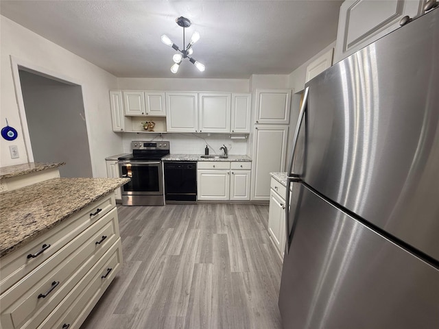 kitchen featuring light stone counters, appliances with stainless steel finishes, light wood-style floors, white cabinetry, and a sink