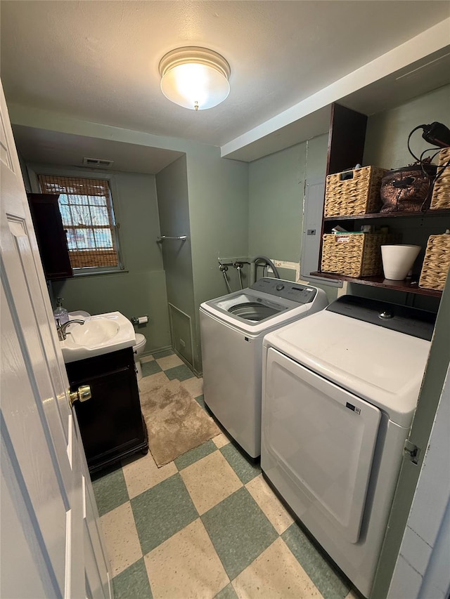 washroom with laundry area, visible vents, independent washer and dryer, light floors, and a sink