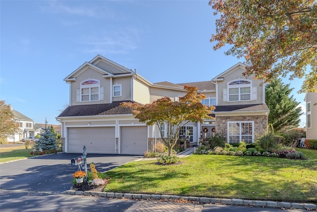 traditional home featuring stone siding, a front lawn, an attached garage, and driveway