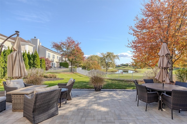 view of patio with outdoor dining space, a water view, a fenced backyard, and an outdoor living space