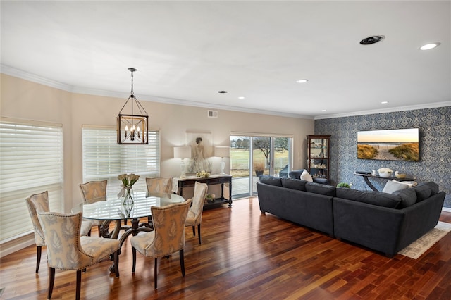 dining space featuring crown molding, an accent wall, wood finished floors, and wallpapered walls