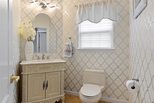 bathroom featuring wallpapered walls, toilet, vanity, baseboards, and tile patterned floors