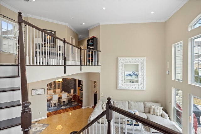 stairway featuring baseboards, ornamental molding, a high ceiling, and recessed lighting