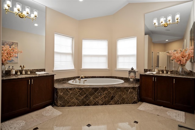 full bathroom with a garden tub, two vanities, a sink, vaulted ceiling, and an inviting chandelier