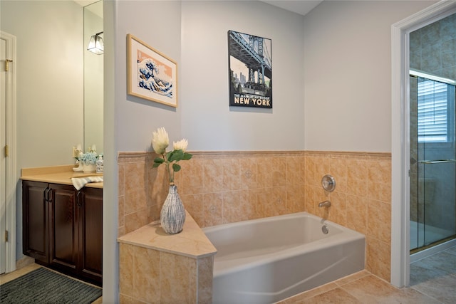 bathroom with a stall shower, tile patterned flooring, vanity, and a bath