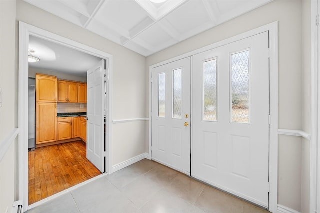 foyer featuring light tile patterned floors, baseboards, and coffered ceiling