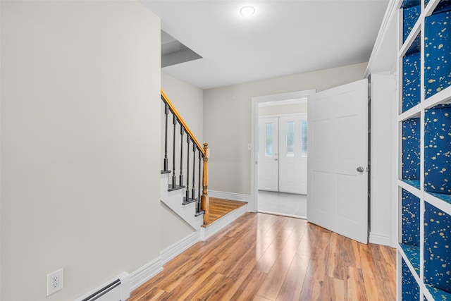 foyer entrance with stairway, baseboards, wood finished floors, and a baseboard heating unit