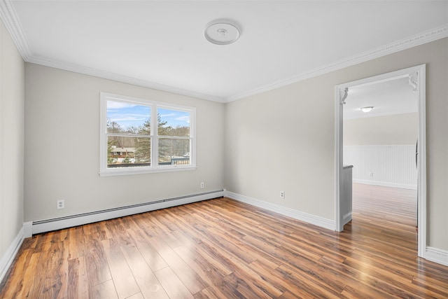 empty room with baseboard heating, crown molding, baseboards, and wood finished floors