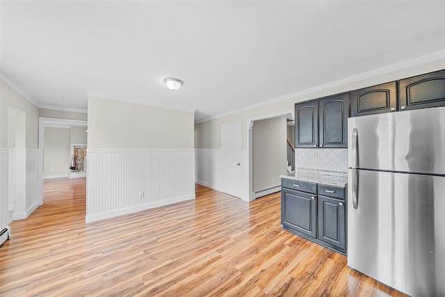 kitchen with a baseboard heating unit, light countertops, wainscoting, freestanding refrigerator, and light wood-style floors