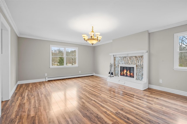 unfurnished living room with a chandelier, ornamental molding, baseboard heating, wood finished floors, and a glass covered fireplace