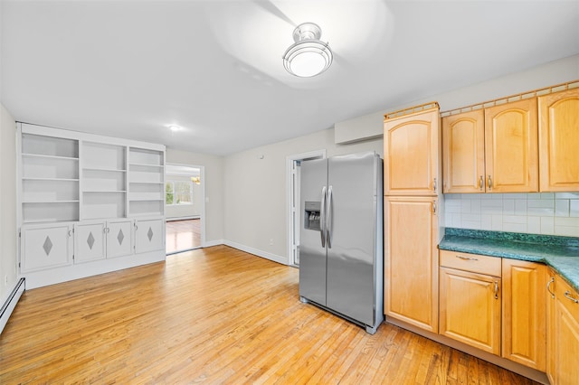 kitchen with light wood finished floors, dark countertops, backsplash, baseboards, and stainless steel refrigerator with ice dispenser