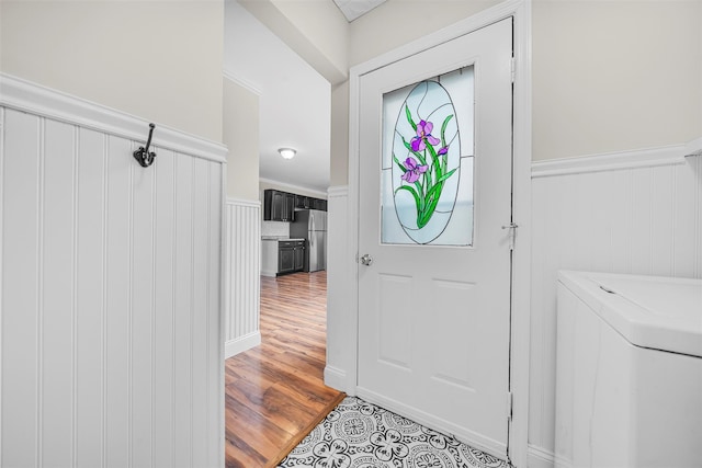 foyer featuring washer / clothes dryer, light wood-style floors, and wainscoting