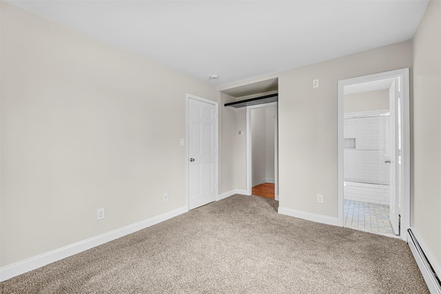 unfurnished bedroom with baseboard heating, carpet flooring, ensuite bathroom, and baseboards