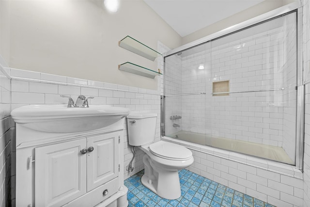 bathroom with vanity, tile patterned flooring, tiled shower / bath combo, tile walls, and toilet