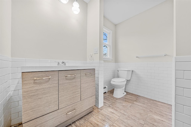 bathroom featuring tile patterned flooring, tile walls, toilet, wainscoting, and vanity