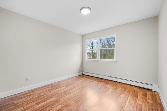 unfurnished room with baseboard heating, baseboards, and wood finished floors