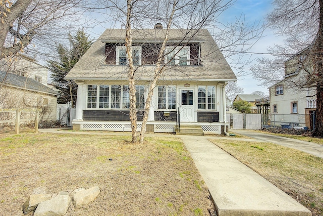 view of front of property with a front yard, a shingled roof, a chimney, and fence